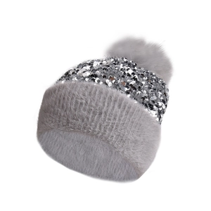 Close-up of gray knit winter hat with silver sequins and fluffy faux fur pom-pom detail