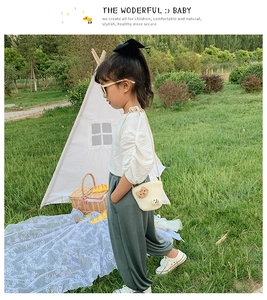 Scatto all'aperto di una bambina con borsa in paglia a forma di orso e abito casual