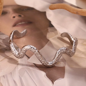 Close-up of wavy silver bangle featuring hammered texture and a unique serpent design