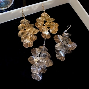 Detailed view of layered cutout leaf tassel earrings in gold and silver finishes