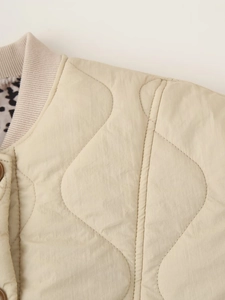Detail of beige quilted jacket featuring leopard print lining and ribbed collar trim