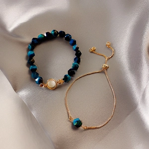 Detailed shot of emerald cut blue beads with golden star and moon charms on silk