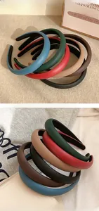 Padded PU leather headbands in various autumn colors stacked on a textured surface