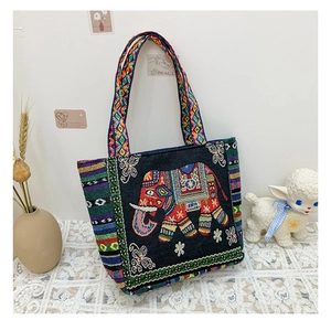 Detail of ethnic canvas handbag featuring colorful elephant embroidery and braided straps