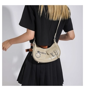 Détail du sac demi-lune abricot avec anneau métallique et poche sur fond sombre