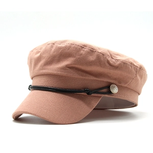 Detail of vintage pink baker boy hat with black cord and golden button