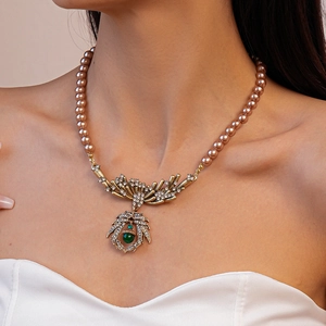 Close-up of vintage gold necklace featuring a green gem pendant and rhinestone details