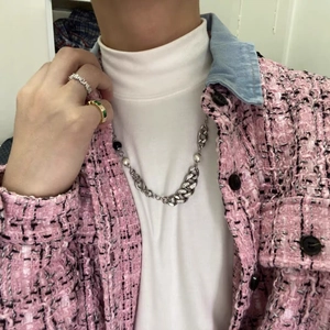 Detail of silver chain necklace with pearls and rings on model in tweed jacket
