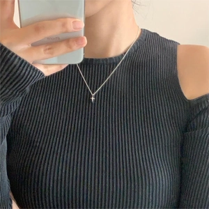 Close-up of a minimalist silver star pendant necklace worn by a model on black fabric