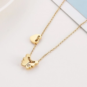 Macro detail of golden butterfly pendant and heart charm on a polished steel chain