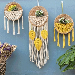 Detail von handgewebten Boho-Wandkörben mit Baumwollfransen und künstlichen Blumen