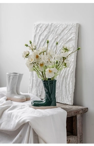 Creative green rain boot ceramic vase with white daisies on a rustic wooden table