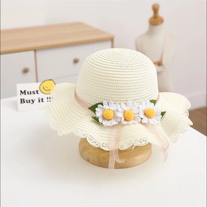 Detail of cream straw sun hat with white daisies and pink ribbon for children
