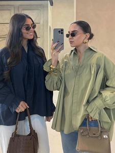 Detail view of loose long-sleeve shirts in black and olive green with stylish accessories