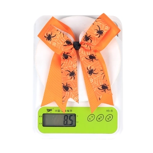 Macro detail of Halloween orange grosgrain ribbon bow with spider pattern on a digital scale