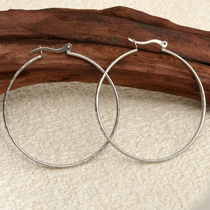 Macro shot of silver 304 stainless steel hoop earrings placed on a rustic wood block