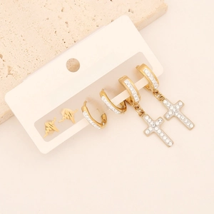 Detail view of gold lightning stud, crystal hoop earrings, and cross pendants set