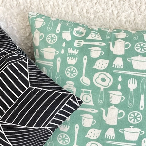 Detail of mint green kitchen illustration and geometric line pattern on linen pillowcases
