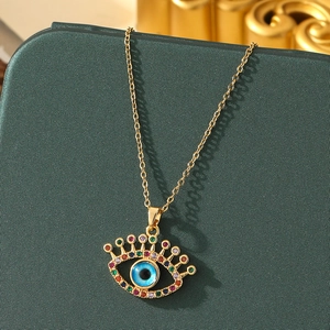 Detail of evil eye necklace pendant with blue center and colorful stones in gold finish