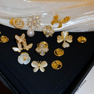 Detailed close-up of golden floral and butterfly brooches with zircons on black box