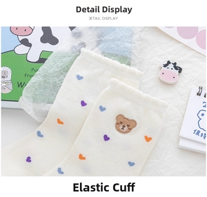 Detail of elastic ruffled cuff on cream bear embroidered socks with colorful hearts