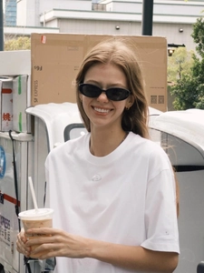Close-up of white heavy cotton T-shirt with embossed logo and oval sunglasses