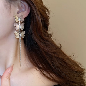Close-up of gold butterfly tassel earrings with sparkling rhinestones on model