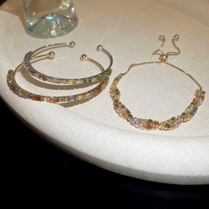 Close-up of luxury gold and silver bracelets with colorful zircon stones on a soft tray