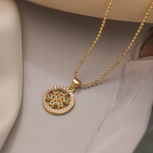 Detailed view of Tree of Life pendant with green zircon stones on golden chain necklace
