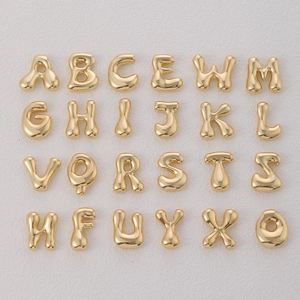 Macro shot of 18k gold plated bubble letter pendants in a clean matrix layout