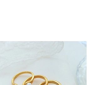 Detailed view of stacked 18K gold plated rings with elegant pearl accents on lace fabric