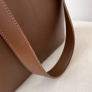 Detailaufnahme des zweifarbigen braunen Lederriemens mit präzisen Nähten an der Tasche