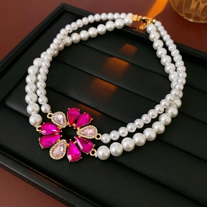 Dettaglio di collana di perle a doppio strato con ciondolo floreale in zircone rosa