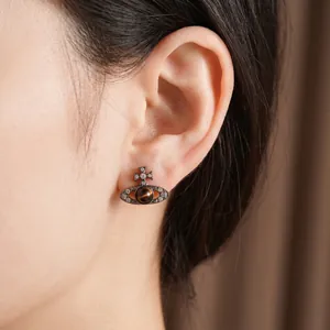 Boucles d'oreilles Saturne en argent vintage avec œil de tigre sur l'oreille du modèle