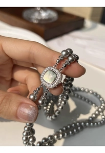 Close-up of a double-layered grey pearl necklace with a square micro-pave shell pendant