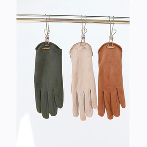 Three pairs of knit gloves in dark green, beige, and caramel hanging for display