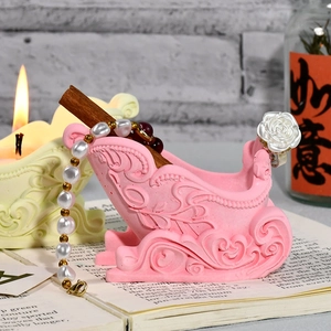 Bougie en forme de traîneau rose avec motifs en relief sur fond de livre ouvert