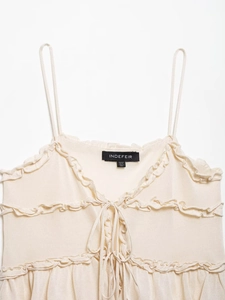 Detailed macro view of cream knitted camisole with ruffled trims and lace-up front design