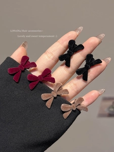 Three pairs of mini velvet bow hair clips in red, black, and brown shown on a sleeve