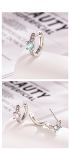 Détail de boucles d'oreilles huggies argentées avec pierres principales en zircon rond