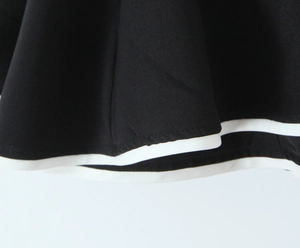Detail view showing black dress hem with white double-stripe trim and quality stitching
