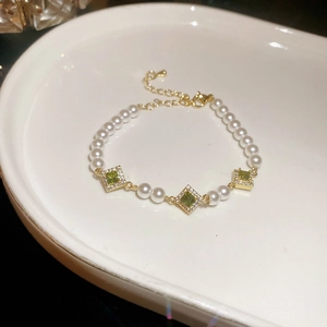 Macro view of vintage gold bracelet with green square stones and white pearls