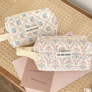 Detailed top view of floral quilted toiletry bags on a woven texture background