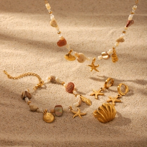 Golden beach jewelry set with shell and starfish charms on sand for a summer look