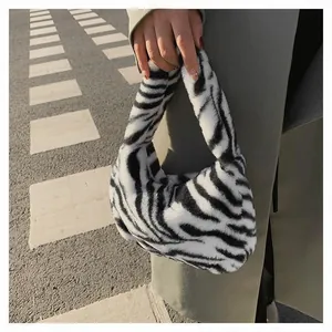 Detail of zebra pattern plush handbag with soft faux fur texture held by model