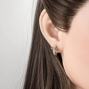 Silver shooting star earring with micro-set zircon stones worn on a model's ear