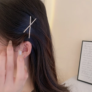 Close-up of a silver crisscross hair clip with sparkling rhinestones worn by a model