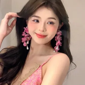 Close-up of pink fabric petal long tassel earrings with drop pearl on female model