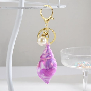 Detailed shot of creative marble texture seashell keychain with pearl and gold lobster clasp