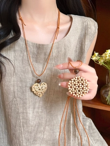 Detail of woven heart and round pendants with wooden beads on a long bohemian necklace